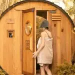 Woman entering the cedar barrel sauna for a sauna for stress relief session at SILA Miami's outdoor sanctuary in Upper Buena Vista, FL