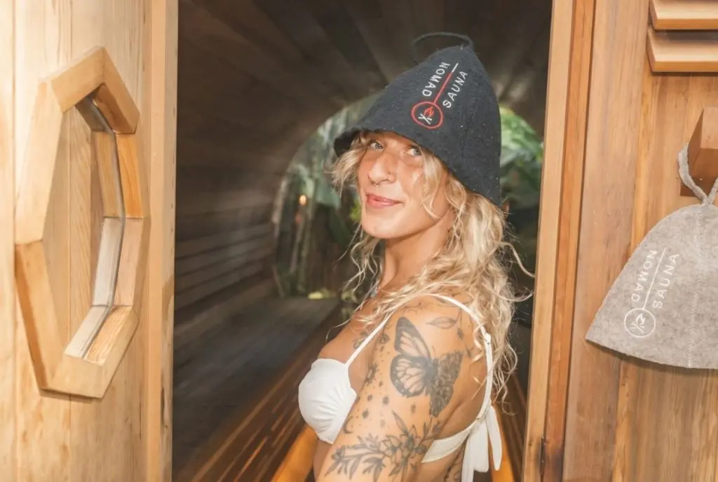 Smiling woman stepping into the sauna as part of a recovery routine for stress and anxiety management at SILA Miami in Upper Buena Vista, FL