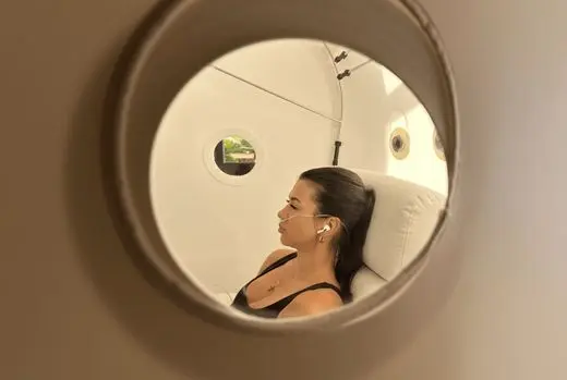 View through the porthole of a hyperbaric oxygen chamber showing a client during an HBOT for brain fog session at SILA Miami, FL.