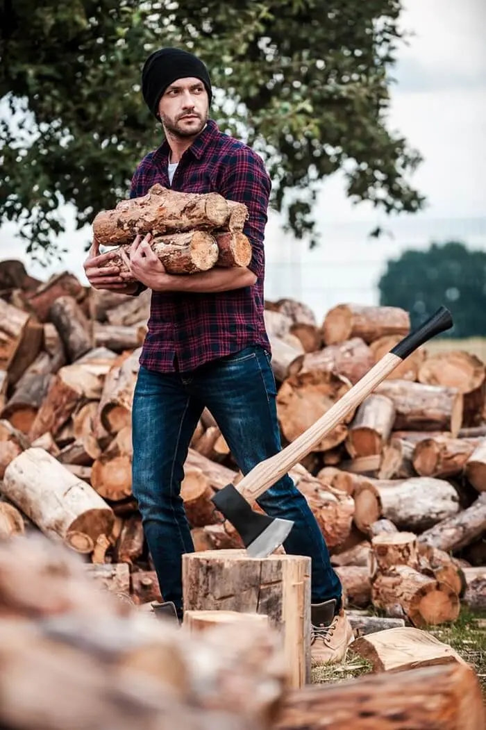 Tree service worker cutting felled logs into firewood