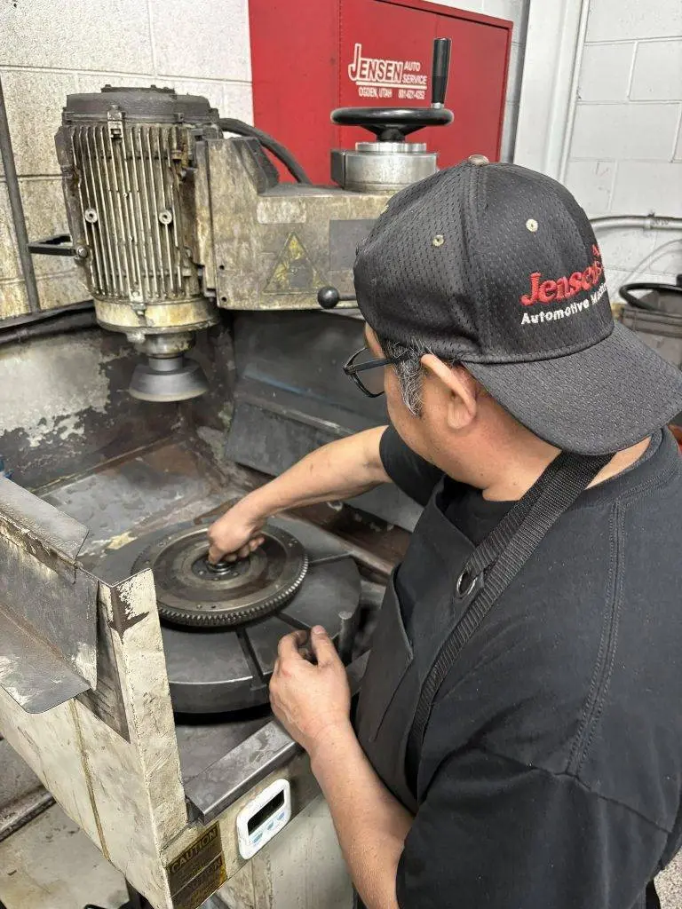 A man wearing a hat and black apron working on a machine