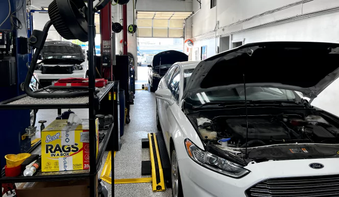 A white ford vehicle inside a auto repair shop