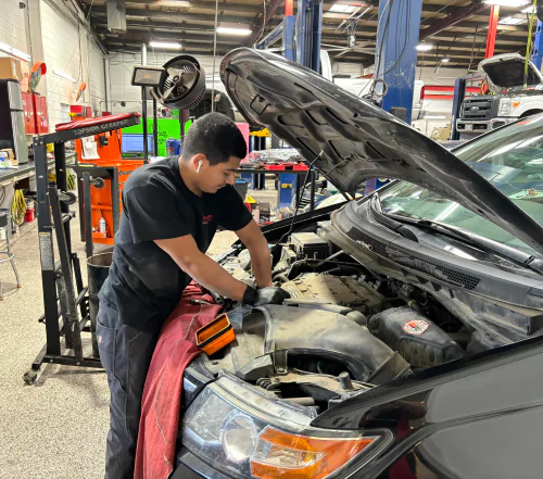 A mechanic wearing a black shirt and pants fixing a car