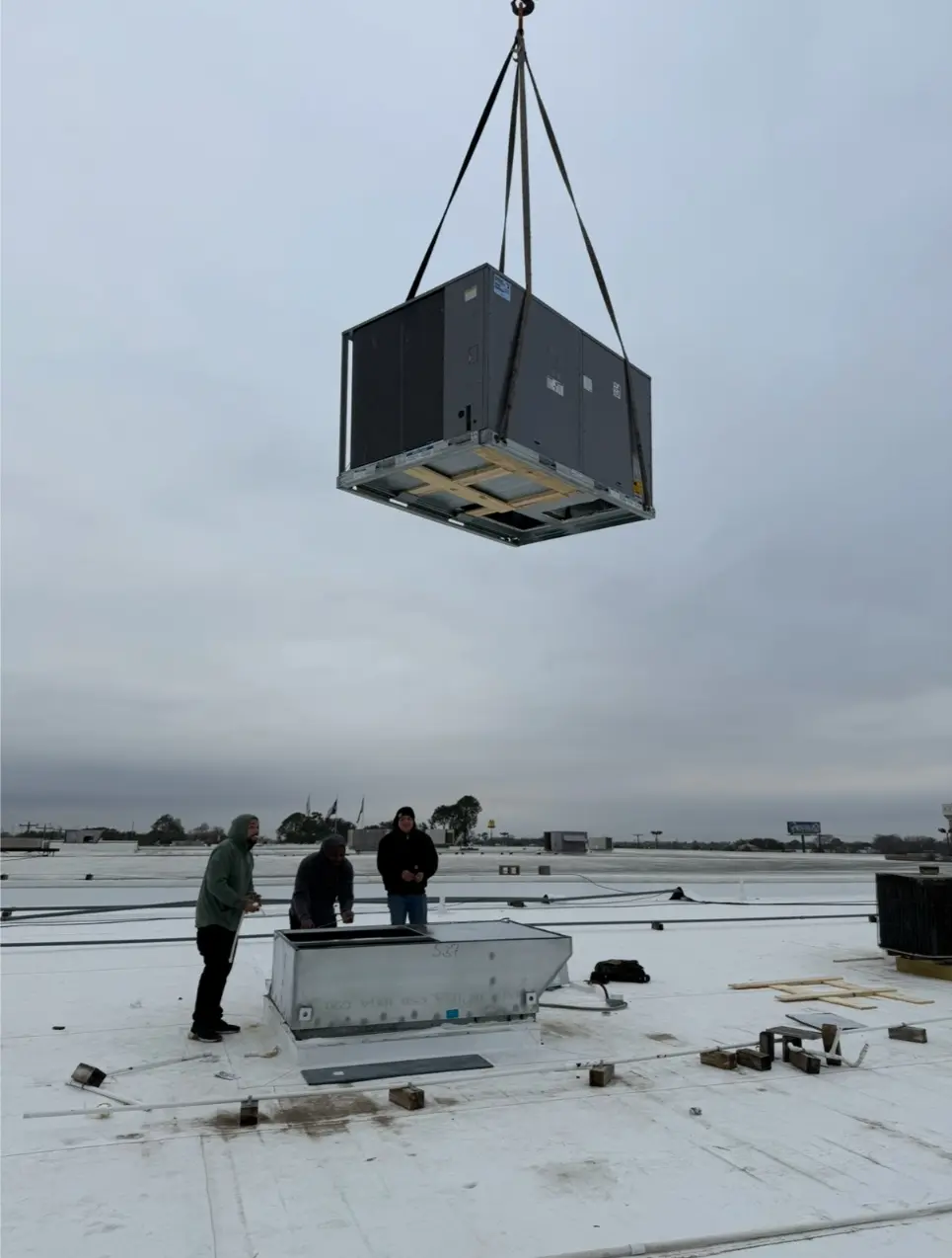 On The Way crew lowering commercial rooftop HVAC unit by crane