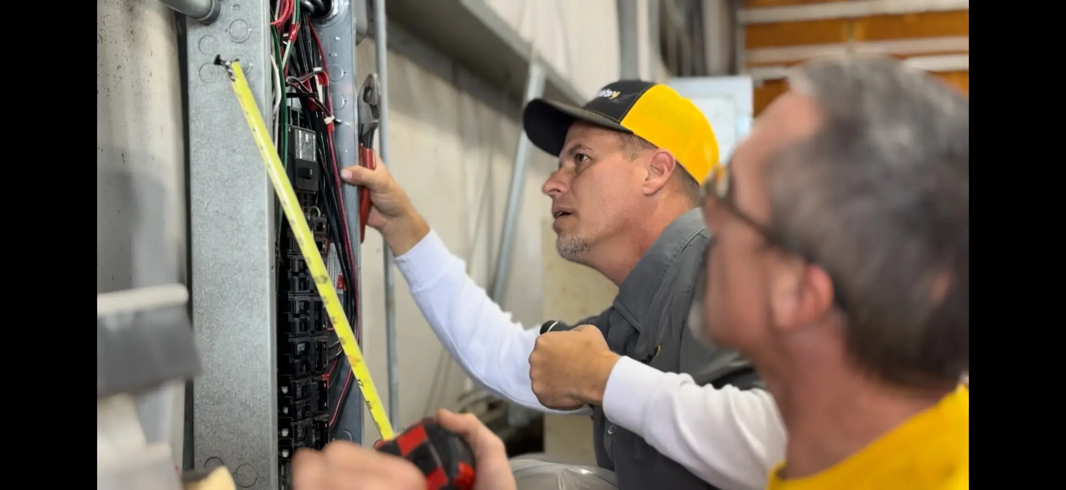 Two electricians inspecting breaker panel