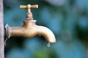 Brass faucet with a slow drip, illustrating a method to prevent frozen pipes during cold weather.