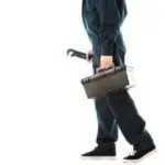 A professional plumber in work attire carrying a toolbox and wrench for emergency plumbing services in Colorado Springs.