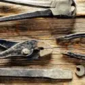 Assorted plumbing tools on a wooden surface, highlighting the importance of maintaining plumbing systems and addressing issues with aging infrastructure.