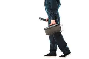 Plumber carrying a toolbox and wrench, symbolizing 24-hour emergency plumbing services for residential and commercial needs.