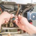 Technician repairing a heating system with tools, showcasing HVAC maintenance by B&L Plumbing.