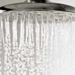 Showerhead with water flowing, showcasing a sleek silver finish for modern bathroom upgrades by B&L Plumbing.