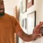 Man adjusting a smart thermostat on a wall, demonstrating modern HVAC technology for efficient temperature control in homes.