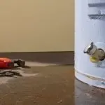 Water heater with visible plumbing fittings and tools, highlighting maintenance or replacement needs in plumbing services.
