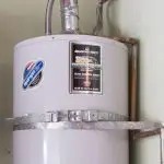 Water heater mounted on a wall showing brand label and hoses, representing plumbing maintenance by B&L Plumbing.