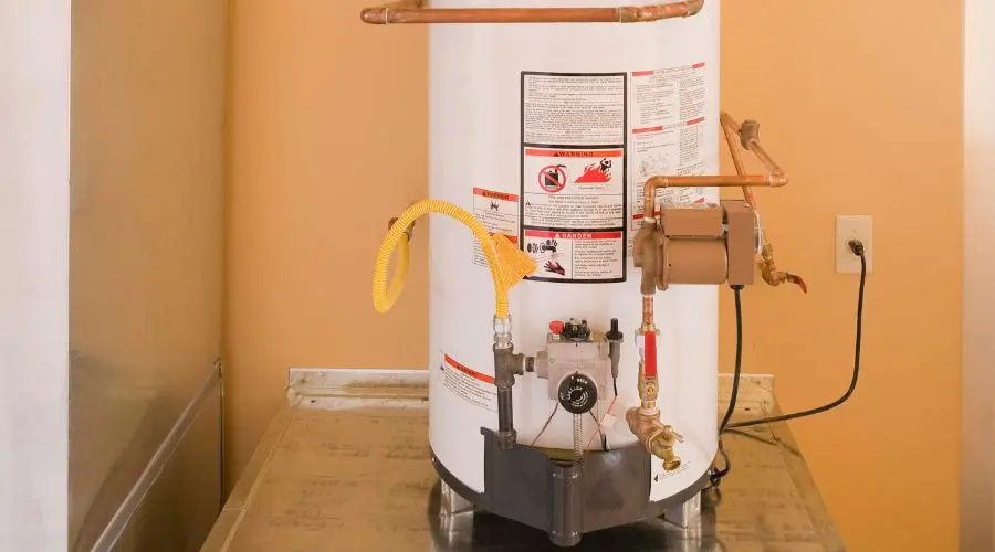 Water heater with safety labels, copper pipes, and gas line for plumbing maintenance at Bud's Plumbing & Repair Service.