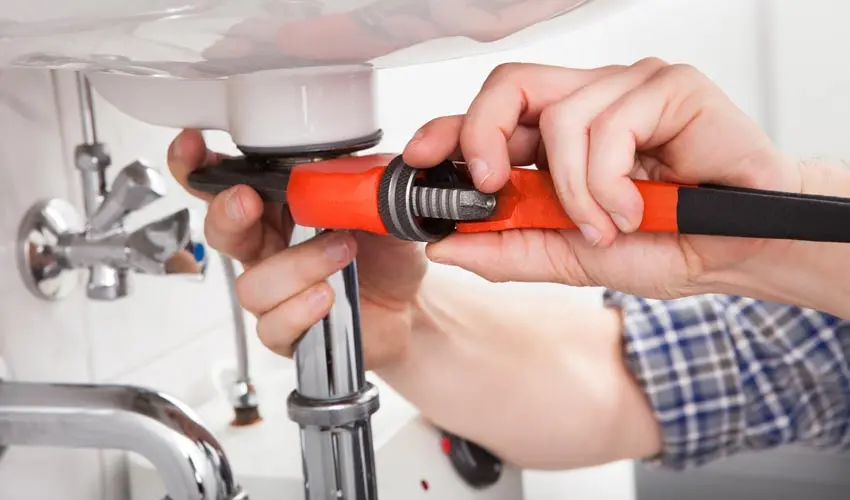 Plumber using a wrench to repair a sink, demonstrating expert plumbing installation and repair services in Evansville.