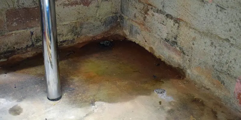 Slab leak damage showing water pooling on concrete floor with visible staining and corrosion, relevant to Bud's Plumbing slab leak repair services in Evansville, IN.