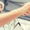 Two individuals shaking hands in a professional setting while discussing plumbing services and repairs.