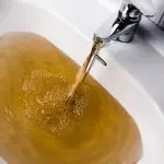 Faucet and sink with brown water, indicating plumbing issues needing repair by Bud's Plumbing & Repair Service.