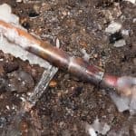 Frozen copper plumbing pipe with ice buildup, illustrating winter plumbing issues and the importance of prevention measures.