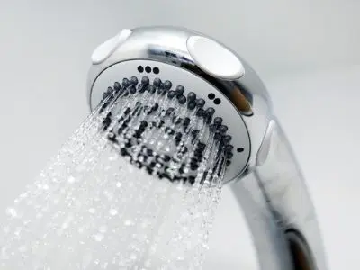 Low-flow showerhead with water flowing, emphasizing water-saving devices for reducing summer water bills.