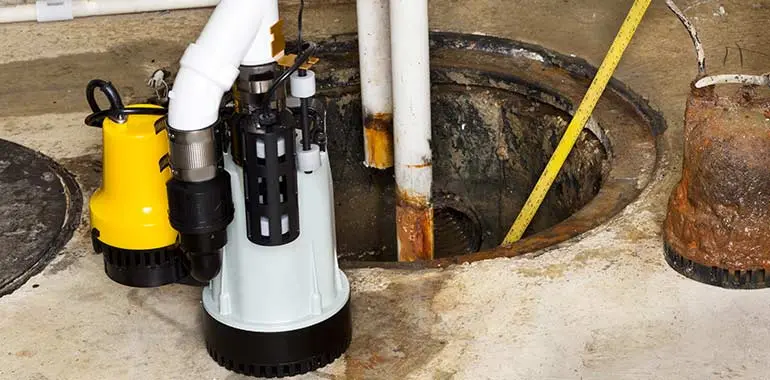 Sump pump installation in basement, featuring a new pump beside a sump pit, highlighting water damage prevention services by Bud's Plumbing & Repair Service in Evansville.