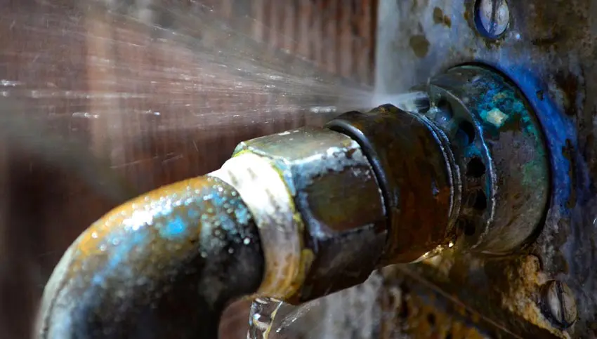 Leaking pipe with water spraying from a rusted fitting, highlighting plumbing issues relevant to Bud's Plumbing & Repair Service's repiping solutions in Evansville.