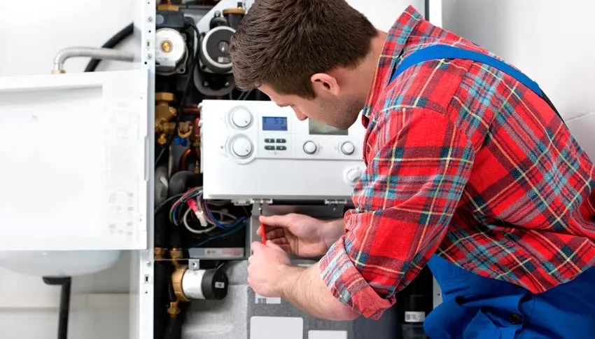 Service technician repairing a boiler, focused on maintenance and installation, emphasizing professional boiler services in Evansville, Indiana.
