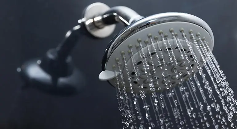 Showerhead with water flowing, representing scald-free products offered by Lambert Plumbing & Heating, Ltd for safe plumbing solutions.
