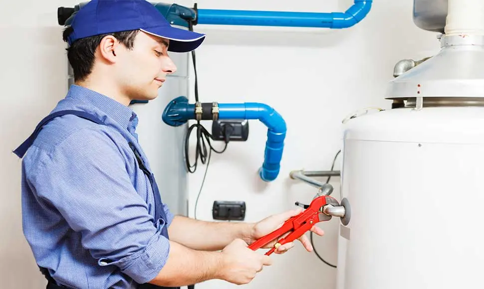 Plumber using a wrench to repair a water heater in North Vancouver, emphasizing Lambert Plumbing & Heating's water heater maintenance services.