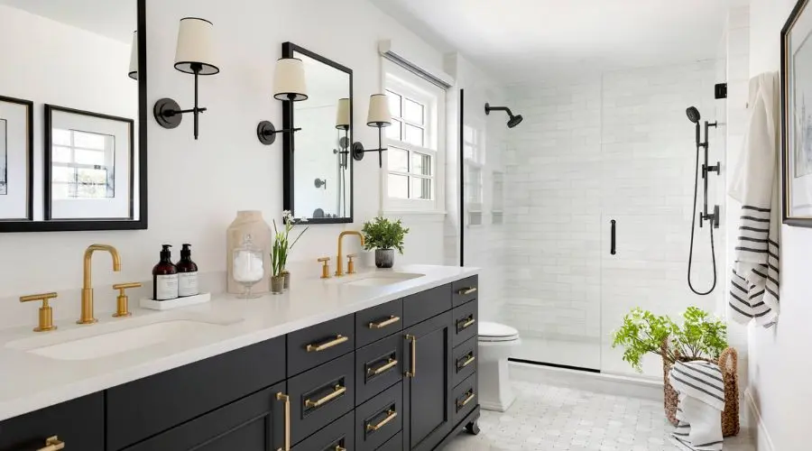 Modern bathroom interior featuring a sleek black vanity with gold fixtures, a glass shower enclosure, and stylish wall sconces, reflecting a contemporary design ideal for bathroom remodels.
