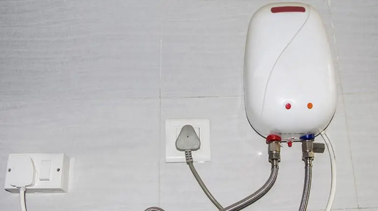 Air-source heat pump water heater mounted on a wall, with visible electrical and plumbing connections, emphasizing energy-efficient heating solutions for homes.