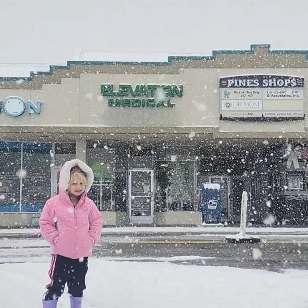 Child in pink coat standing in snow
