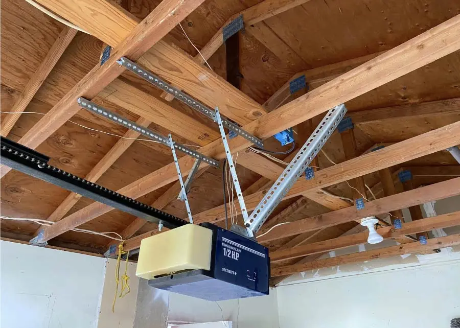 Chamberlain garage door opener mounted to a ceiling with its cover removed, showing the internal parts.