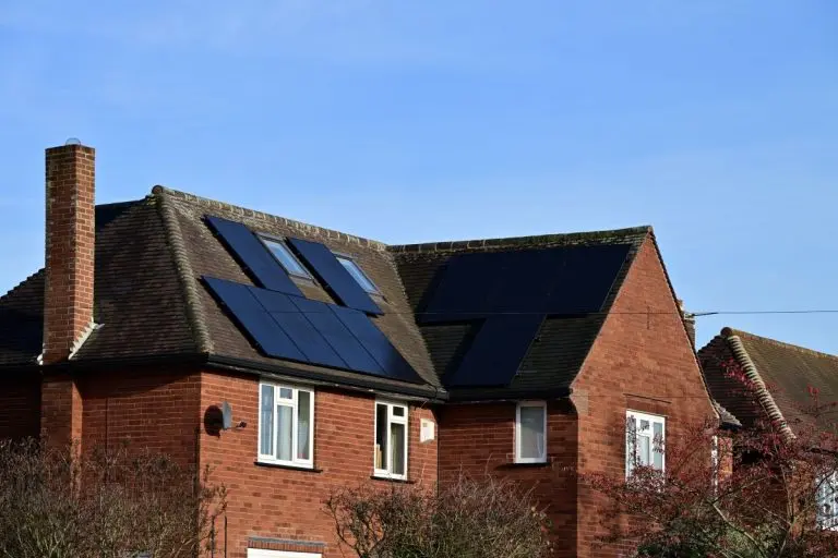 Red brick house roof with multiple residential solar panels