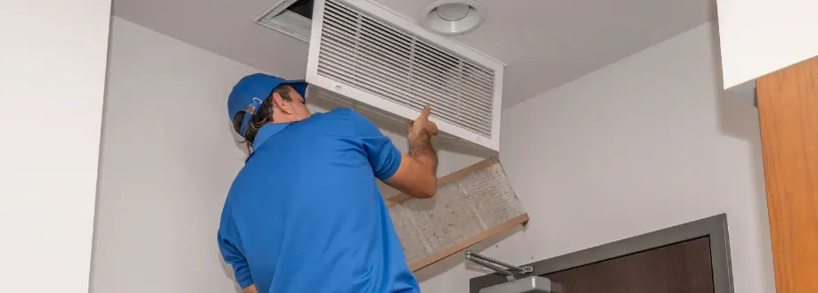 a technician works on an HVAC vent in the ceiling