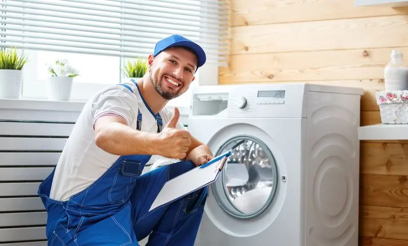 working man plumber repairs  washing machine in laundry