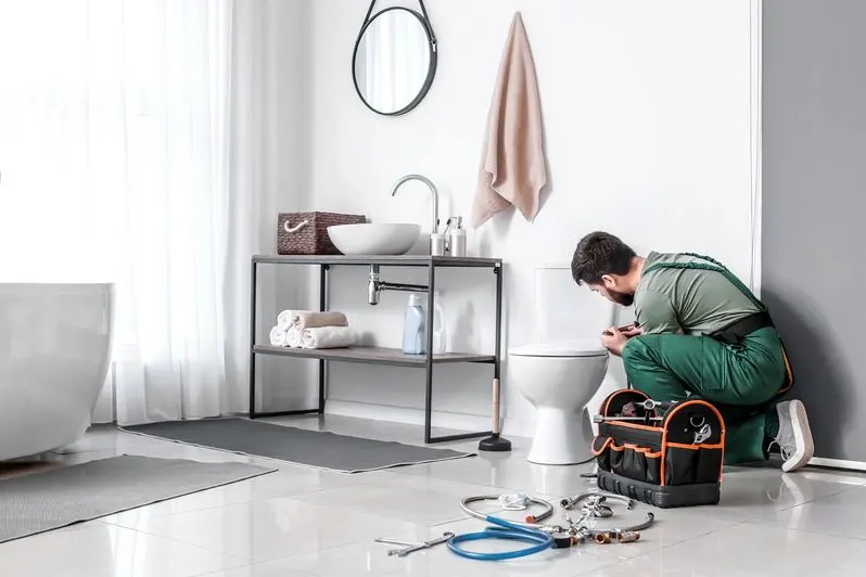 Plumber installing toilet bowl in bathroom