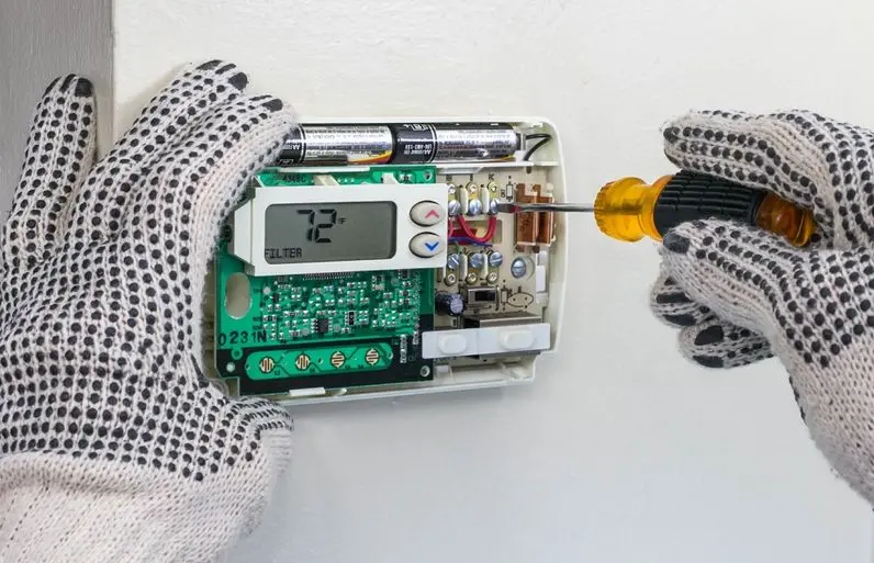 Technician repairing digital heating and cooling thermostat