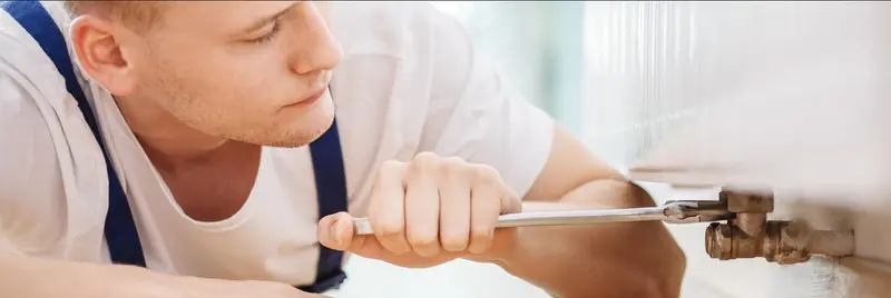 plumber tightening screws in pipe using screwdriver