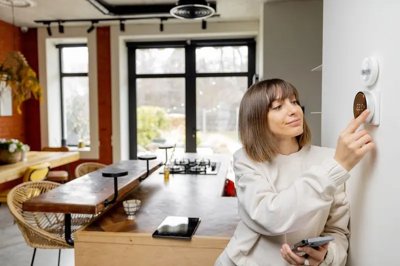 Woman adjusting her smart thermostat at home