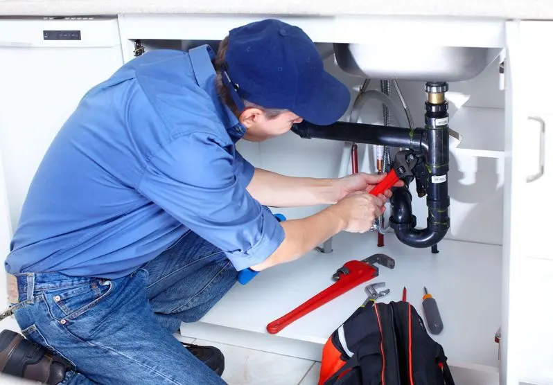 Plumber inspecting the pipes underneath a sink
