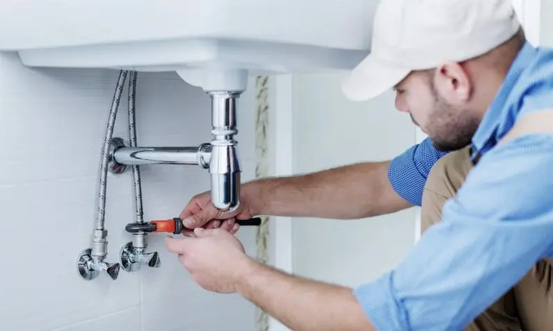 male plumber fixing a sink in bathroom