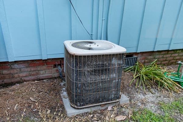Old air conditioner system compressor next to home
