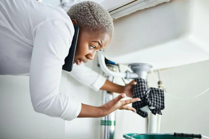 Woman having a under the sink plumbing emergency