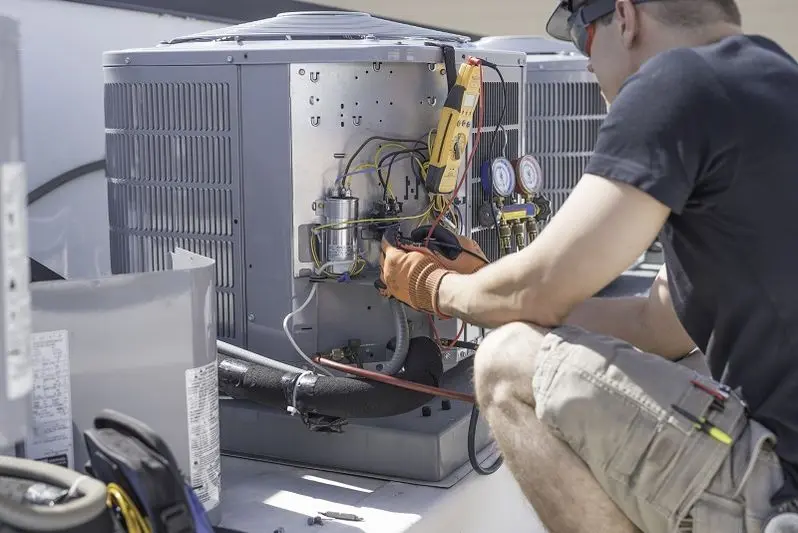 HVAC technician working on controls of air conditioner