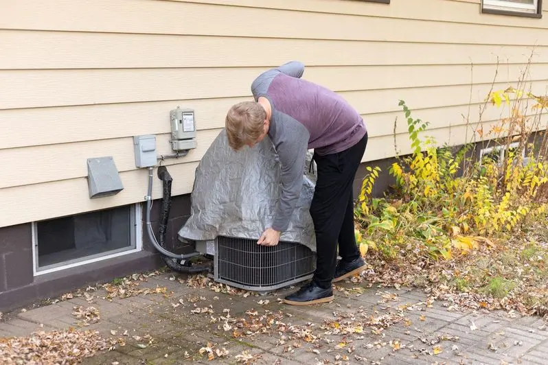 Man putting on an outdoor AC cover