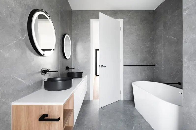 Stylish spacious bathroom with round mirror above sink and wooden tabletop