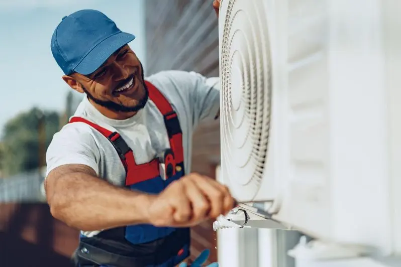 Smiling HVAC technician installing an outdoor AC unit