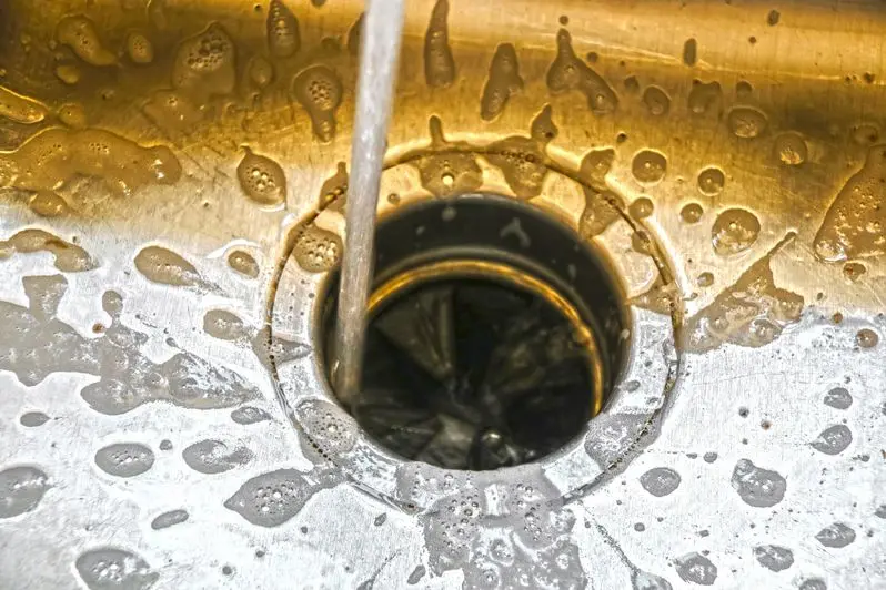 Water running into a garbage disposal of a stainless steel sink